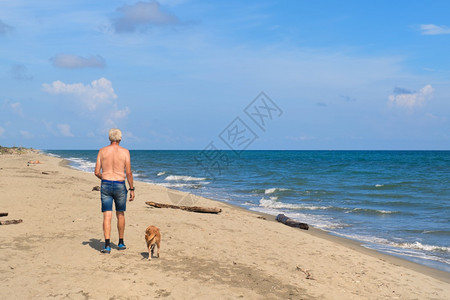 帽地中海欧洲男人和他的狗在科西嘉海滩图片