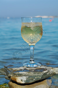 经过送达白色的海浪冲刷岩石边杯白葡萄酒被海浪冲洗过图片