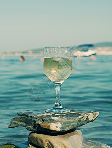 放松白色的海浪冲刷岩石边杯白葡萄酒被海浪冲洗过送达图片