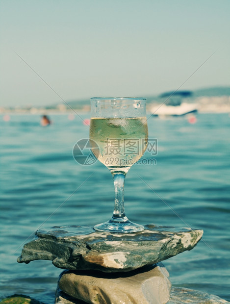 放松白色的海浪冲刷岩石边杯白葡萄酒被海浪冲洗过送达图片