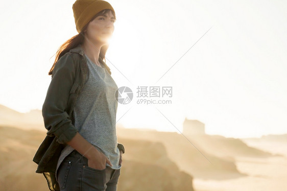 悬崖一种美丽的女人有黄色帽子看着海滩享受风景步行图片