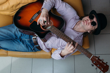 男幸福服装白种男人躺在沙发上弹声吉他图片