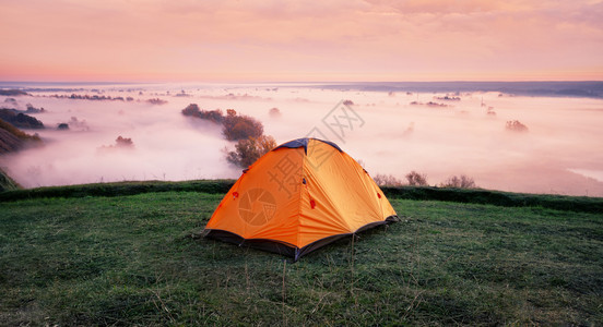 清晨在迷雾河上山坡的橙色帐篷旅行自由和隐私的概念在迷雾河上山丘的橙色帐篷极端冒险橙子图片