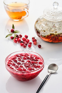 自然红色的吃在玻璃碗和茶壶里白色背景的cranberry果酱图片