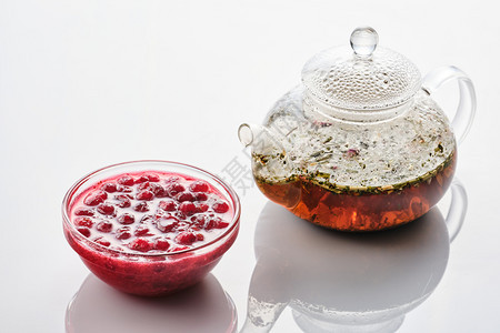 一种越橘多汁的在玻璃碗和茶壶里白色背景的cranberry果酱图片