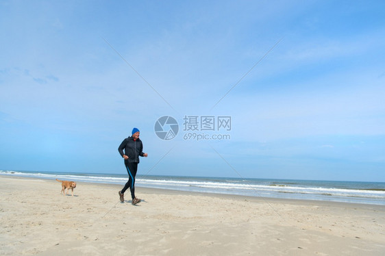 男人和狗在沙滩上奔跑图片