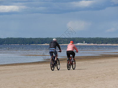 俄罗斯在海滩骑自行车的一对夫妇无法辨认的人男和一个女运动积极的图片
