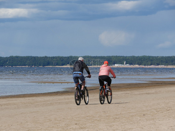 俄罗斯在海滩骑自行车的一对夫妇无法辨认的人男和一个女运动积极的图片