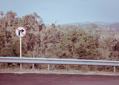 路护栏在古老效应中具有山地背景的右转禁止标志石灰图片