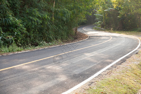 驾驶坏的箭沿着山坡弯曲道路从山上向下弯来公路两侧还有更多的树林图片