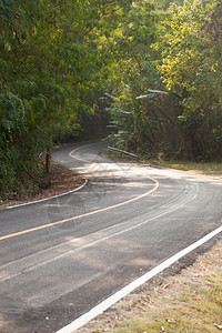 街道弯曲的沿着山坡弯曲道路从山上向下弯来公路两侧还有更多的树林危险图片