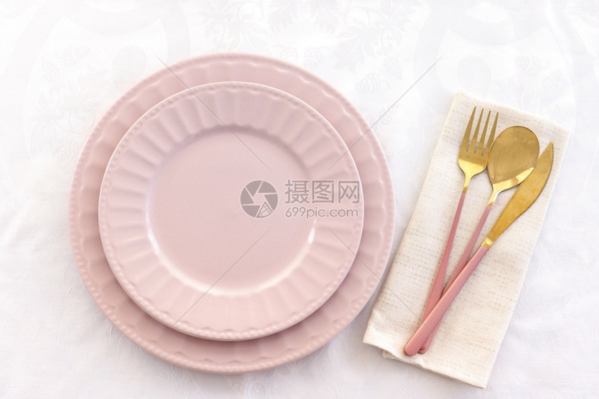 白色的生日在桌布和粉红色金叉刀和纸巾上的勺子提供两张粉红色板亚麻布图片