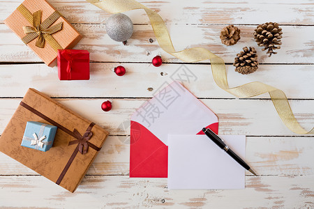 白色的一种空圣诞信和笔放在一个生锈的木制桌子上面有礼物装饰品和松果仁圣诞信上面是生锈的木制桌子上图片