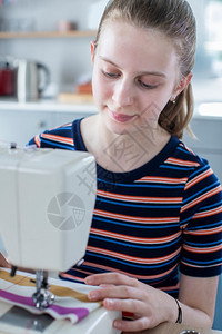 孩子少女学习如何在家里使用缝制机器老的乐趣图片