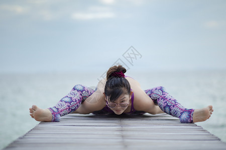 美丽的女人在海木码头做瑜伽在海龟上摆姿势假期海滩活动图片