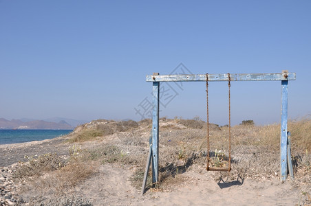 休闲的童年一种古老和生锈摇摆在希腊海滩上图片