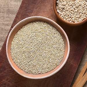 在木板上用天然光照拍的奎诺阿麦片将原白色quinoalatChenopododiumquinoa谷物种子投在碗里饮食健康生的图片