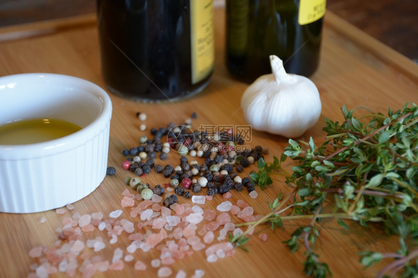 一份拉面盘上的橄榄油一瓶巴萨醋大蒜百香粉红盐和木切板上的胡萝卜椒粒切割烹饪图片