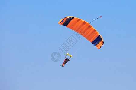 冒险空气高的Skydiver在蓝天Tandem跳跃自由概念Logos和商标将Skydiver从蓝天的橙色降落伞下移走图片
