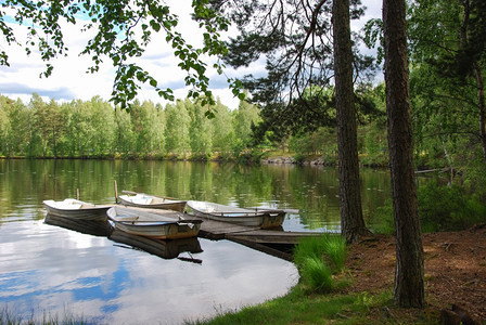 库尔曼浪漫的天空在林地一个瑞典湖的宁静海湾中在一座旧木头码上划船行驶图片