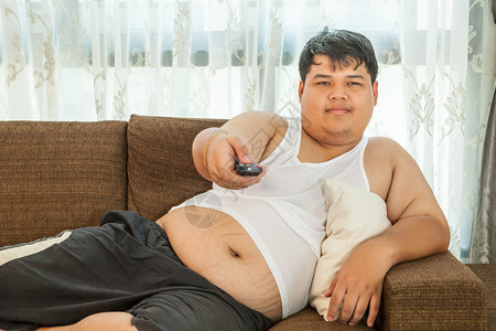 生活腹部肥胖坐在沙发上看电视的超重人图片