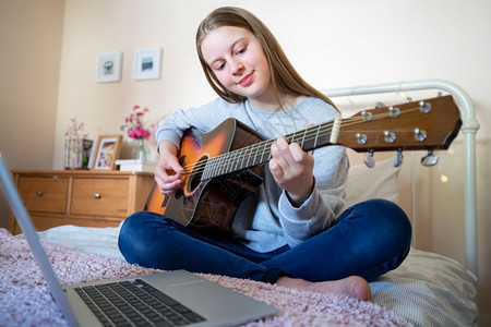 水平的音乐青少年女孩学习如何在笔记本电脑上用在线课程来玩经济吉他白种人图片