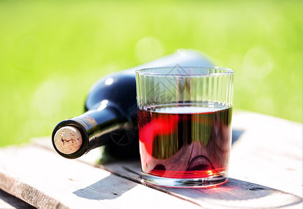 一杯红酒和瓶子躺在木桌上背景模糊一杯红酒和瓶子放在木桌上红色的复制材料图片