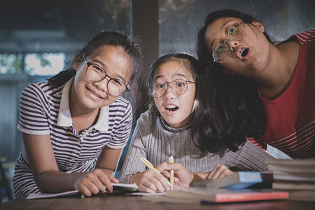 年轻的泰国三个亚裔青少年在家客厅做学校工作乐得开心学生图片