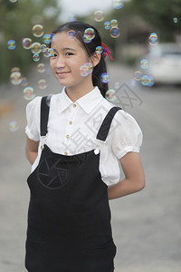 泰国亚裔少年笑面露脸户外放松香皂泡漂浮微笑的图片