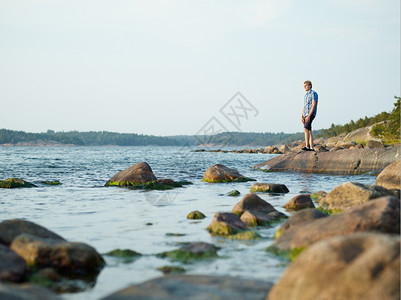 成人英俊的男在岩石海岸上行走美丽的夏天夜晚支撑生活图片