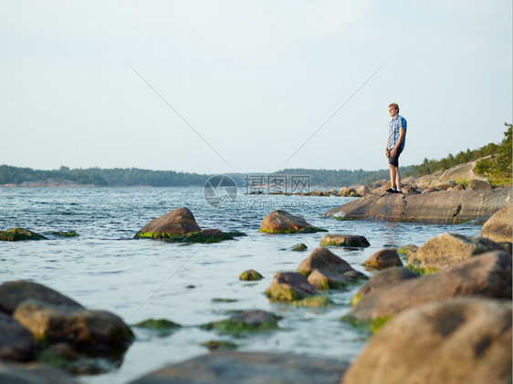 成人英俊的男在岩石海岸上行走美丽的夏天夜晚支撑生活图片