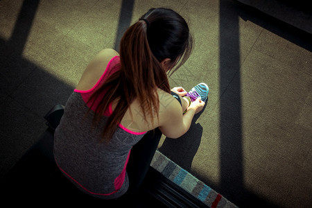 马拉松训练搭售年轻的亚洲女绑着跑鞋的带子准备慢跑图片