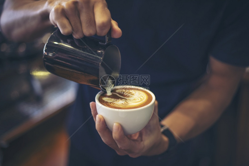 手贴近咖啡师做拿铁画喝浇注牛奶图片