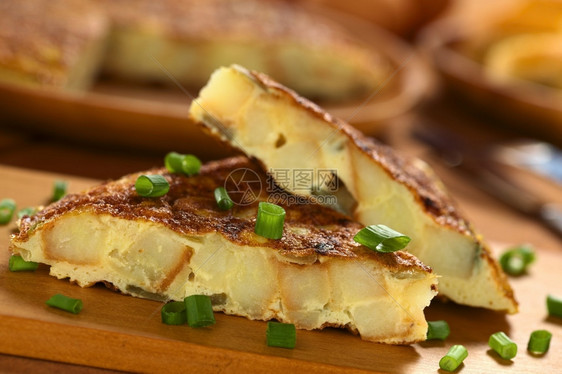 美食油炸正面新鲜的自制西班牙玉米饼煎蛋卷上面有土豆和洋葱片木板上有图片