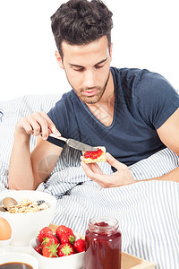 果酱草莓牛角包成人男子在床上用白色背景做早餐的照片该以白人背景为图片