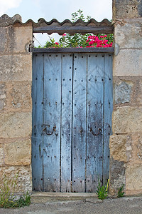 质地在西班牙马洛卡有砖瓦屋顶和粉红色布加林维拉的鲁斯基蓝色旧木制门和西班牙马洛卡带有瓷砖屋顶的鲁斯基蓝色旧木制门粉的老图片