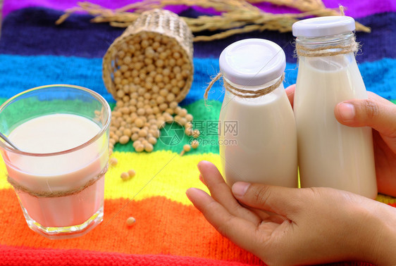 人类手玻璃早餐饮料自制豆浆奶和多彩背景的大豆这种饮料有丰富的蛋白类阿梅加质纤维美味营养健康饮品图片
