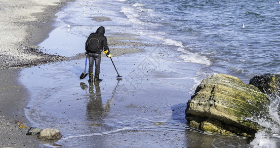 清除ODESSAUKRAINE01257带金属探测器的人在冬季清晨的海滩上寻找宝藏在海滩上的一个宝藏猎人闲暇冬天图片
