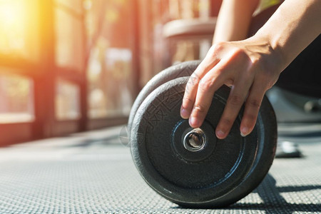 妇女用手在健身房的肌肉结构中安装钢铁哑铃手臂重的健美运动员图片