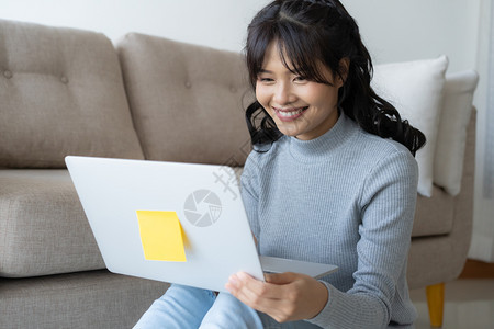在职的亚裔妇女家里使用笔记本电脑亚洲女孩在家工作时坐着微笑女士技术图片