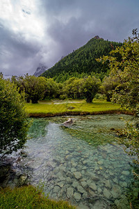 流动的闪电水四川道强县亚丁自然保护区的河流经山林和牧草流向四川道成县图片