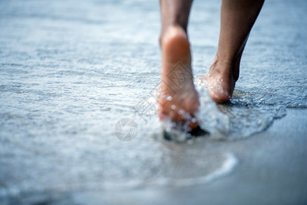 海岸线游客女妇赤脚在海滩上走路图片