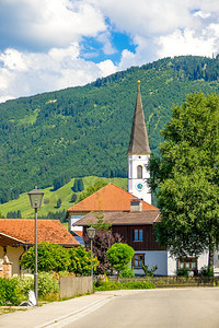 天气路奥地利阿尔卑斯山的一个小村庄桑尼高塔上的教堂钟表和阿尔卑斯山的云雪乡村教堂高山图片