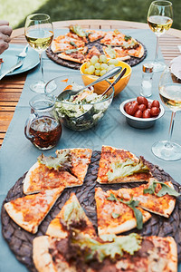 户外周末比萨家庭花园晚餐后院果桌上的披萨沙拉水果和白葡萄酒家庭花园晚餐后院桌上的披萨水果和白葡萄酒图片