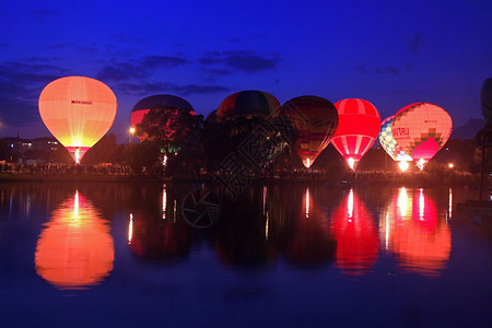 降落热气球在湖边的傍晚天空中飞翔骑反射图片