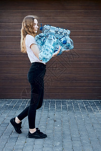 压扁透明女将废旧塑料水瓶扔进垃圾桶的年轻妇女把空用塑料瓶丢弃在垃圾桶里收集塑料废物以回收以便回收塑料污染概念和太多塑料废物图片