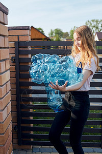 将废旧塑料水瓶扔进垃圾桶的年轻妇女把空用塑料瓶丢弃在垃圾桶里收集塑料废物以回收以便回收塑料污染概念和太多塑料废物保持处理环境的图片