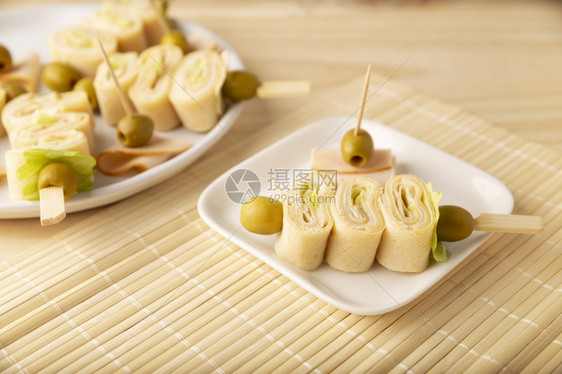 派对配着火腿和奶酪的薄饼卷在一块装有橄榄的棍子上绉莴苣图片