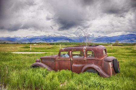 拉根一辆旧车在位于蒙大拿州Harrison附近的农场上生锈其背景是烟草根山弃农田图片