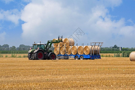 农业现场拖拉机在车上装满了一堆干草车皮稻云图片